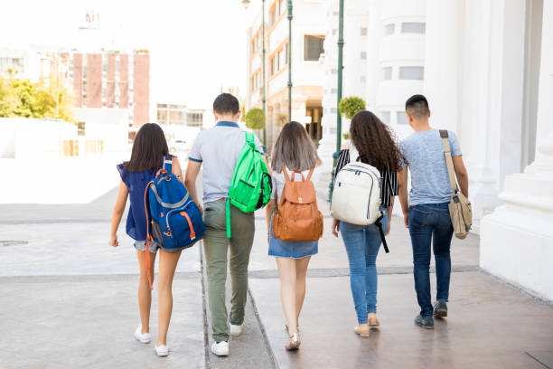 Five teens walking to school with backpacks.
