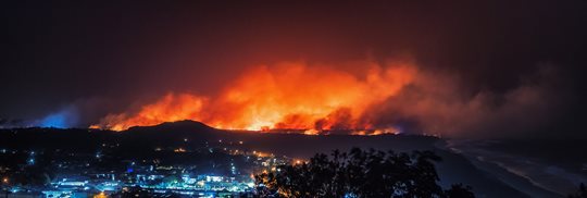Image of a fire on the hills overlooking a town at night