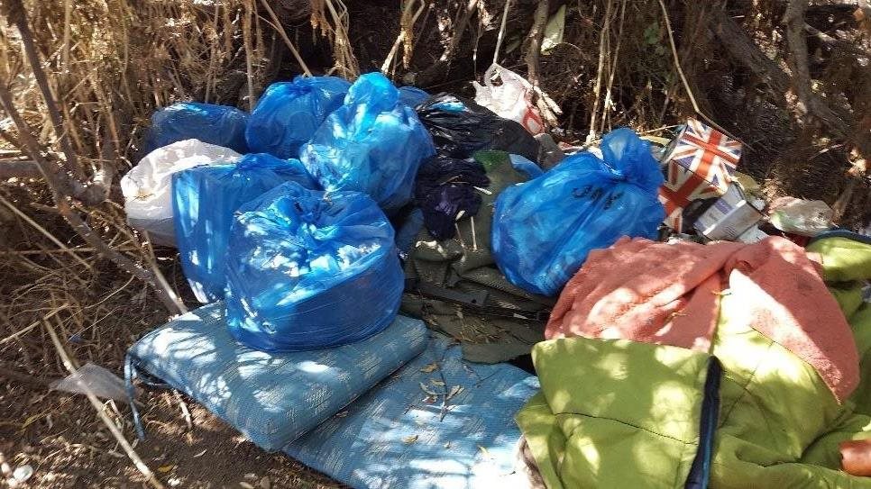 Trash voluntarily collected in blue bags for disposal by unsheltered homeless encampment residents.