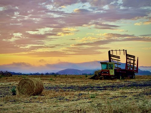 Haybale and tractor with beautiful sunset