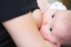 mom holding her baby in her arms and breastfeeding