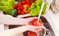 Person washing fruits and vegetables under cold water