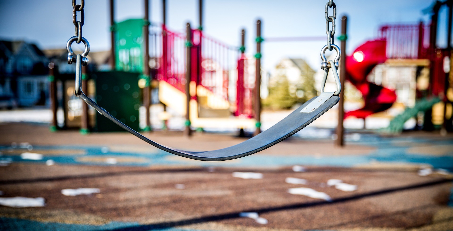 Empty swing with playground in the background