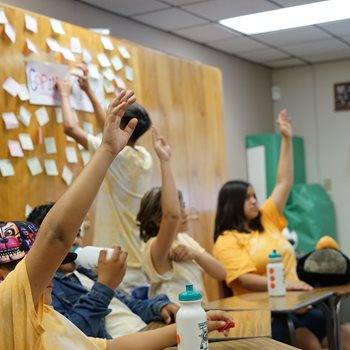Children raising hand in classroom.