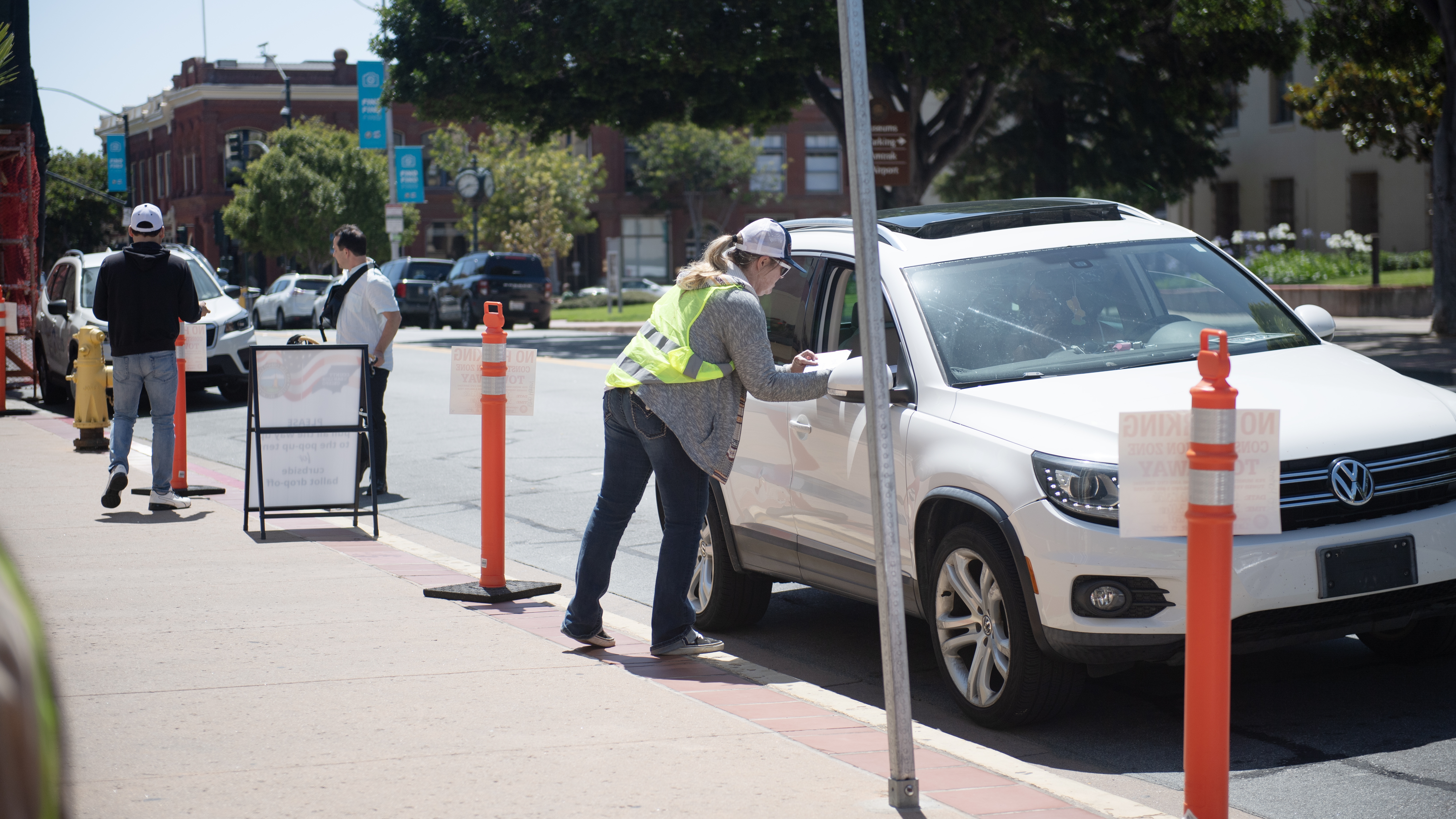 A poll worker retrieves a ballot from a car