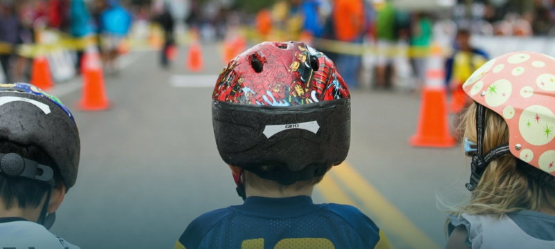 Three young children on bikes wearing helmets