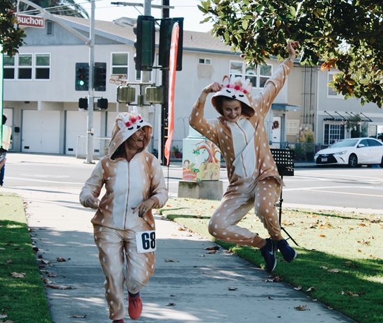 Two girls jumping across the finish line at Reindeer Run