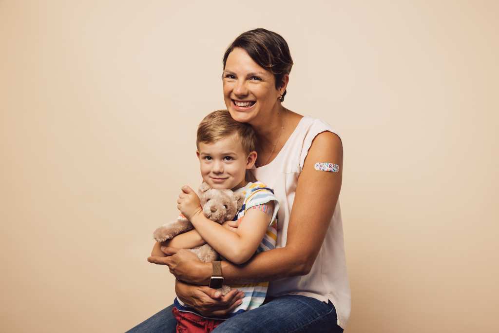 Photo of smiling mom and son with band aids on arms
