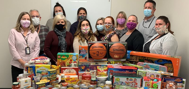 SLO DCSS staff standing behind food and toy donations Click to view article, DCSS Participates in Season of Hope 2020