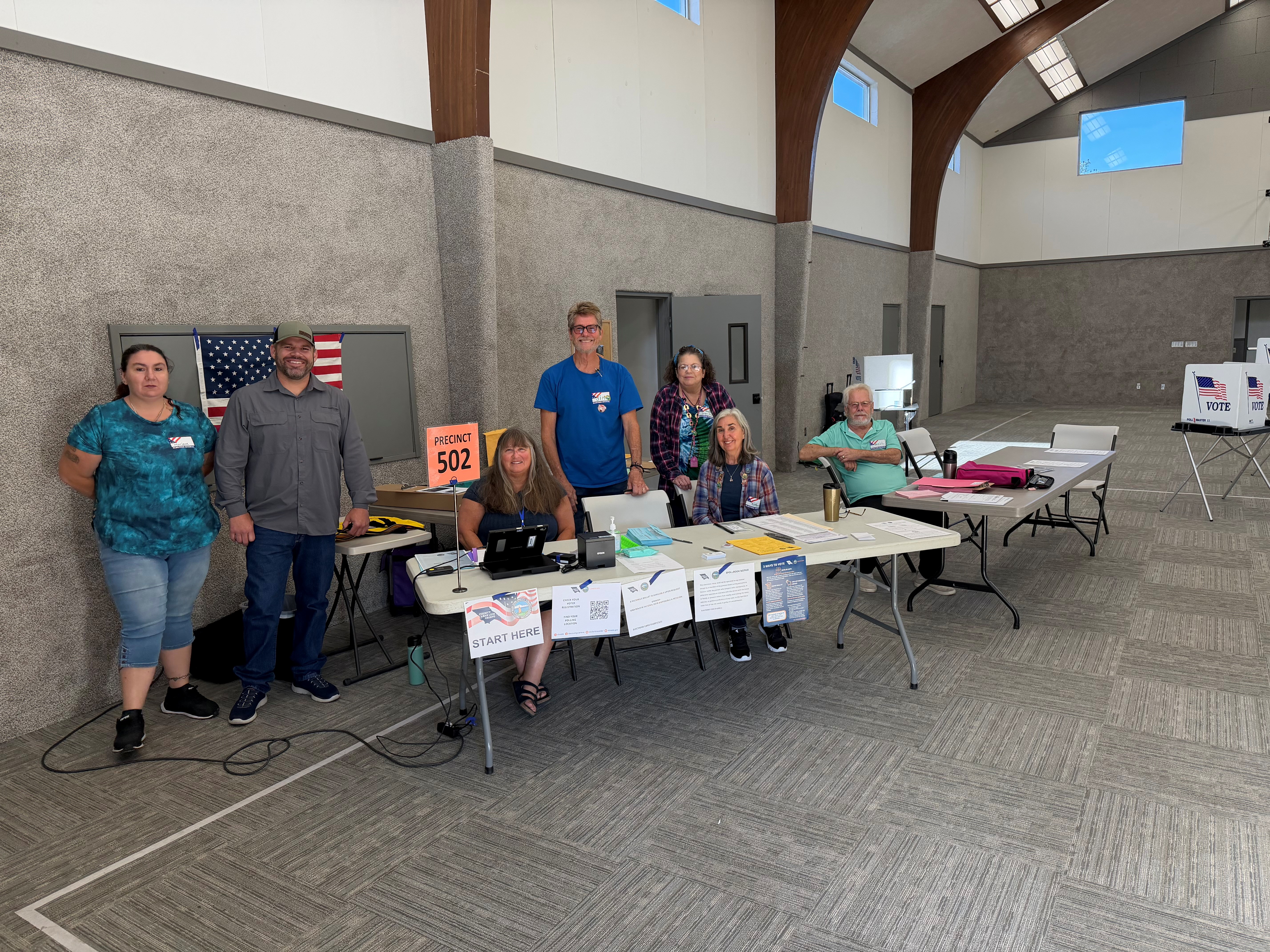 Poll workers standing and sitting at a check-in table on election day