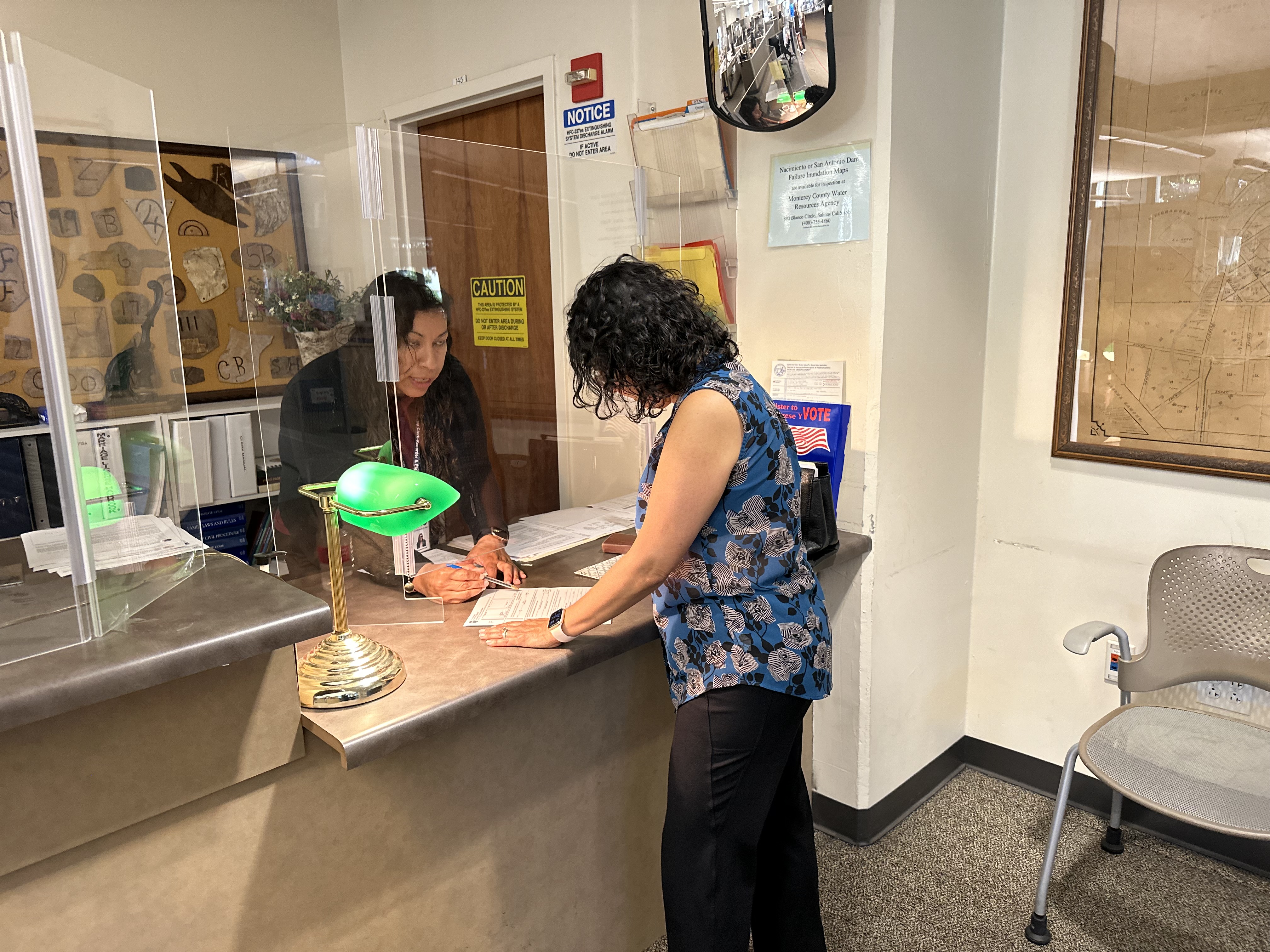 A woman standing at a counter filling out paperwork