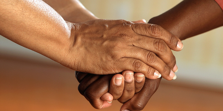 Two individuals holding hands.  Click to view article, A Message to Our Community in This Time of Conflict 