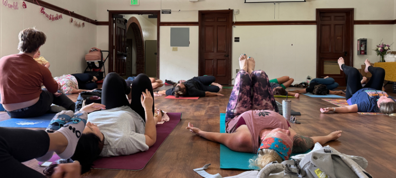 People lying on yoga mats in room with infants